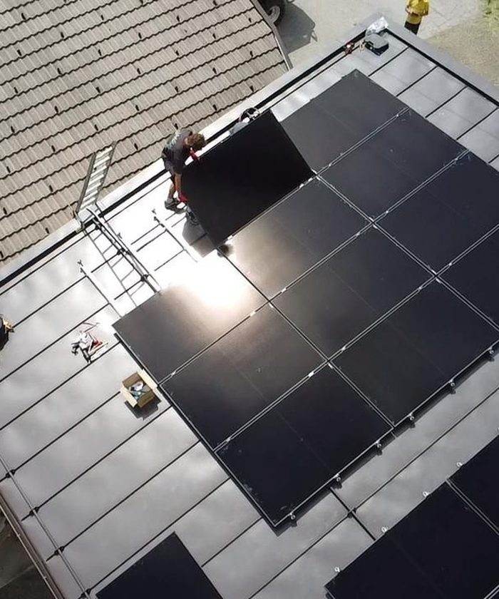 Monteur von ELMETIC setzt ein Photovoltaik-Modul auf einem Blechdach in Osttirol