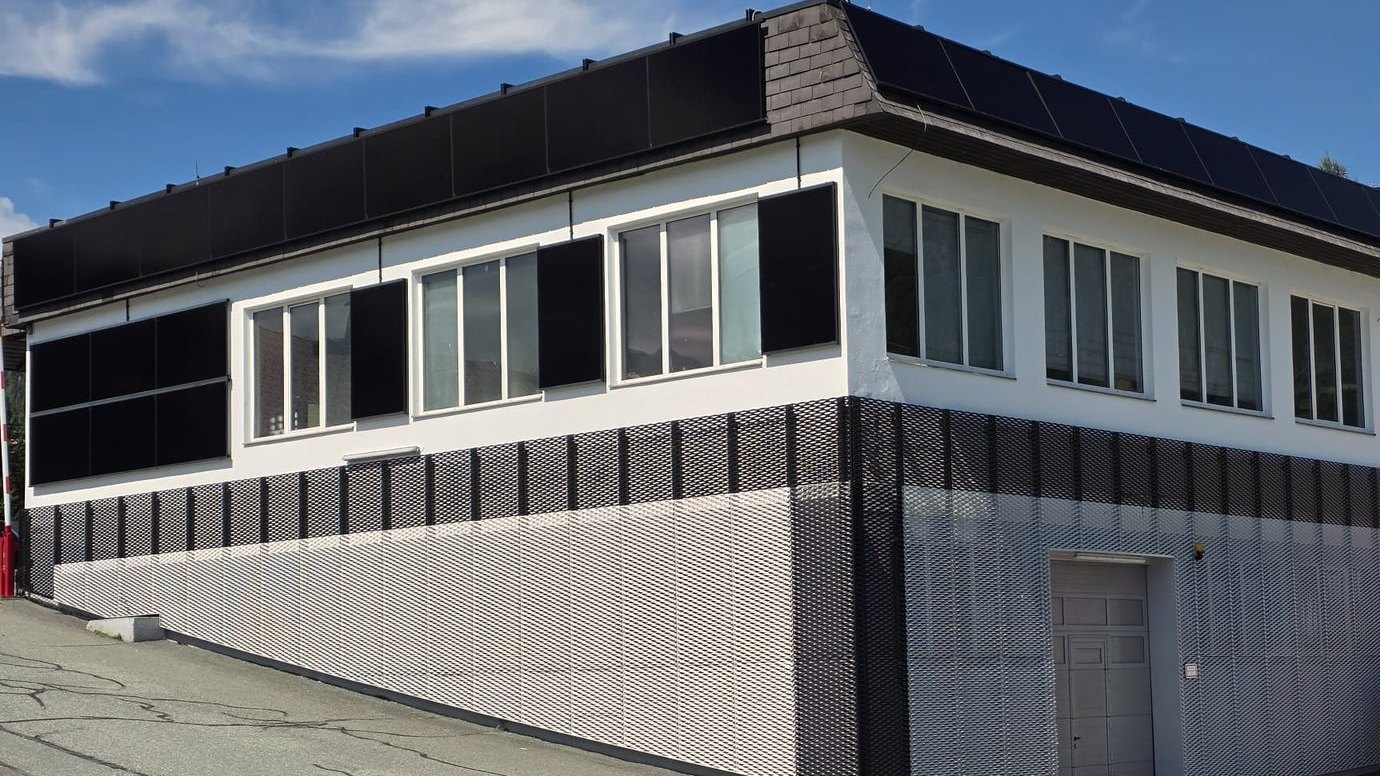 Gebäudeecke mit beiden PV-Flächen: senkrechte Module an der Südfassade, geneigte Module auf einer Unterkonstruktion Richtung Osten